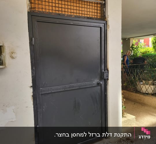 דלת מתכת שחורה עם מסגרת רשת מעליה